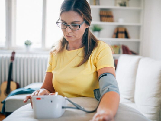 người đang tự đo huyết áp tại nhà để theo dõi sức khỏe tim mạch